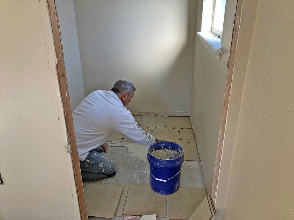 Brad Saum laying floor tile in a bathroom for a Habitat for Humanity build