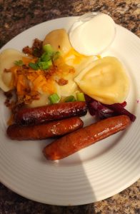 plate of food containing perogies and sausage.
