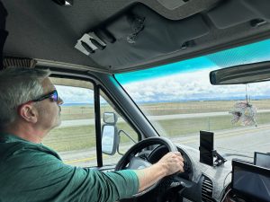 Brad Saum driving a van on a highway looking out into Banff National Park