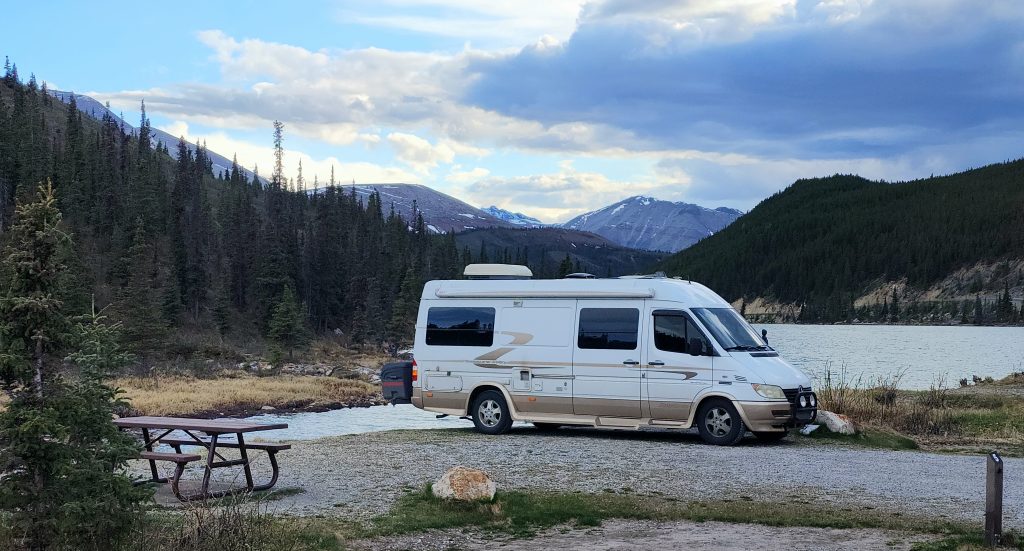 van parked at campsite in mountains by a lake
